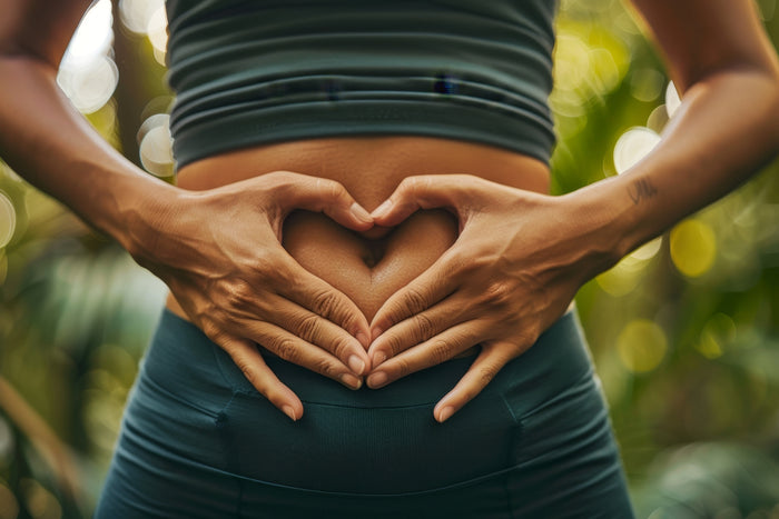 Person forming a heart shape with hands over their stomach, symbolizing gut health and wellness.