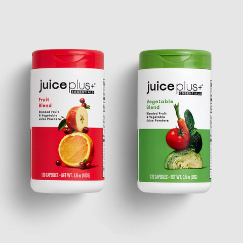 Two Juice Plus+ supplement containers, one for fruit blend and one for vegetable blend, on a light gray background.