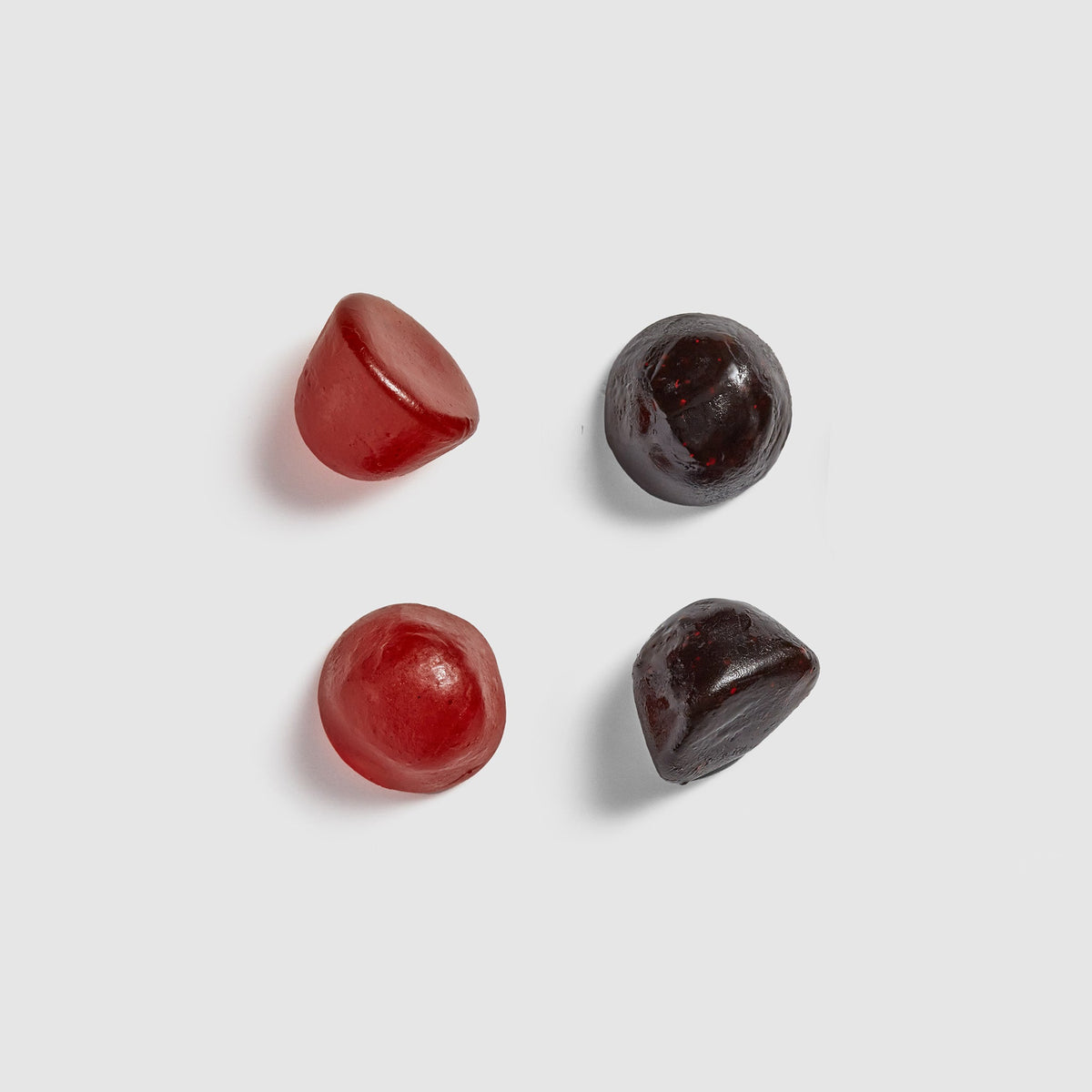 Four red and black Juice Plus+ chewables on a light gray background