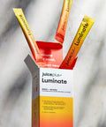 Juice Plus+ Luminate supplement sachets coming out of the box on a marble surface