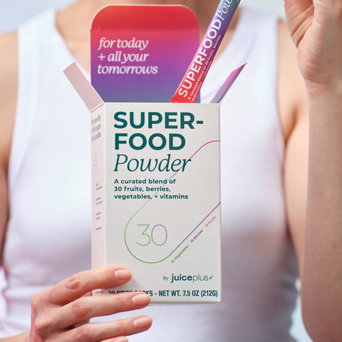 Box of Juice Plus+ Superfood Powder held by a person