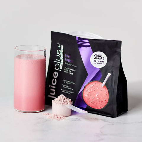 Juice Plus+ Perform Fruit Fusion protein shake mix with a glass of pink shake and scoop on a light background