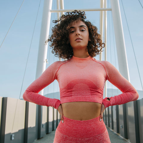 Woman in a pink athletic outfit standing on a bridge