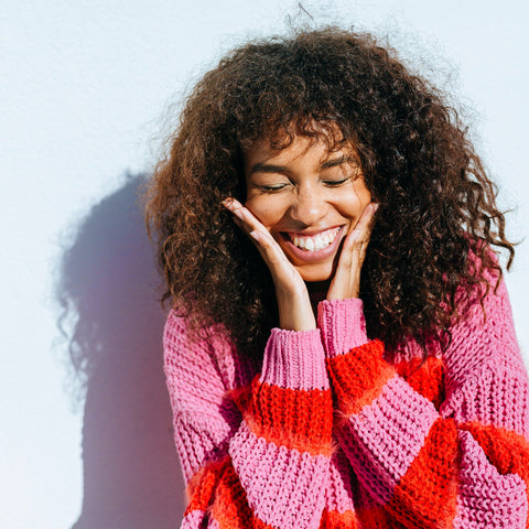Woman wearing a pink and red striped sweater against a light blue background