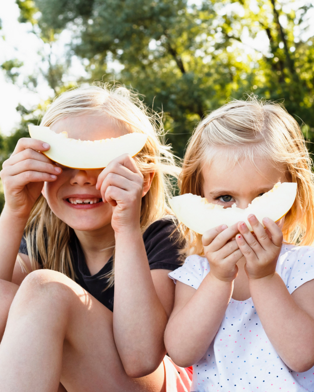 Female children outside holding slices of melons