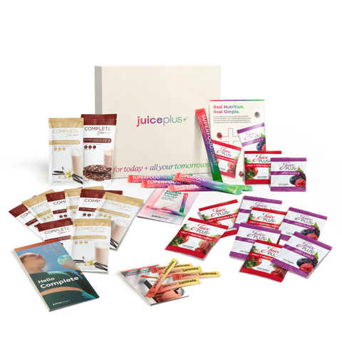An assortment of products, sample cards and packaging from Juice Plus, including superfood powder, Juice Plus+ luminate, complete shake mix, and chewables.