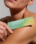 Person holding a Juice Plus+ Super-Biome Prebiotic package on their arm against a neutral background