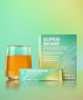 Super-Biome Prebiotic packaging with a glass of juice on a gradient green background