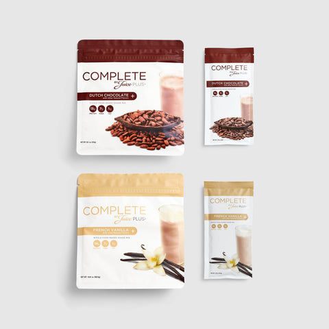 Four packages of Juice Plus+ Complete variety Shakes, two with chocolate flavor and two with vanilla flavor. Each package has an image of ingredients like chocolate chips and vanilla pods.
