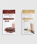 Two packages of Complete Food Variety Shakes, one with chocolate flavor and one with vanilla flavor. Each package has an image of ingredients like chocolate chips and vanilla pods.